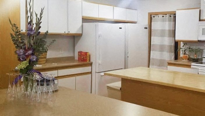 A kitchen with a table and a vase of flowers on it.